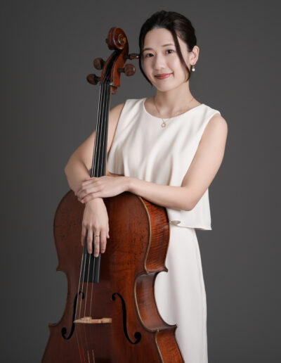 グレー背景で撮影したチェロを持った女性音楽家のプロフィール写真